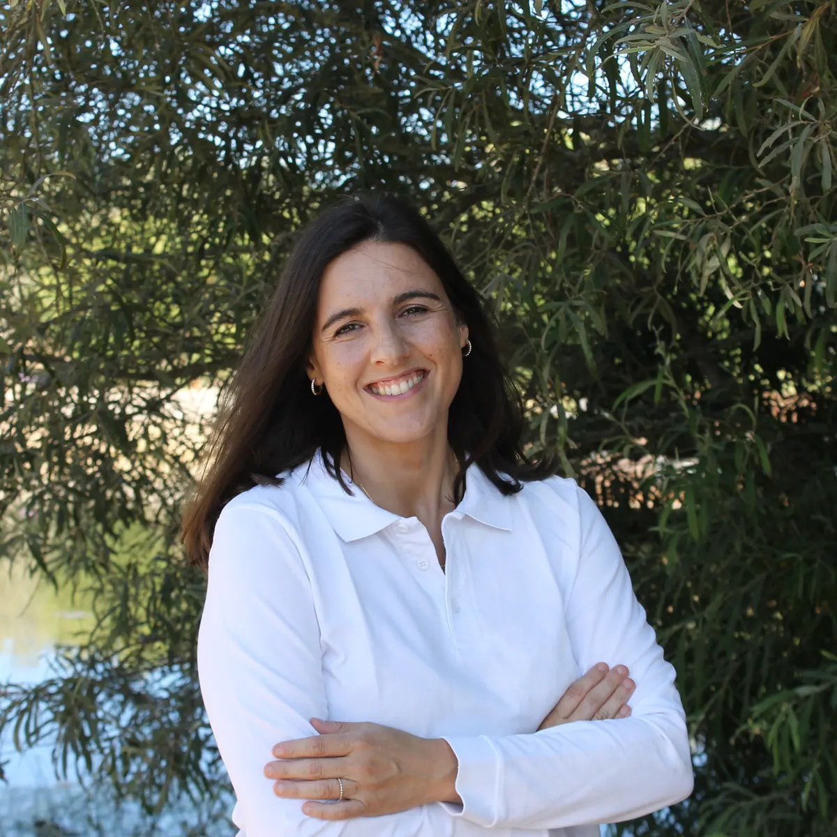 Tânia Frausto, enfermeira de reabilitação e instrutora de yoga, ao ar livre junto a uma árvore.